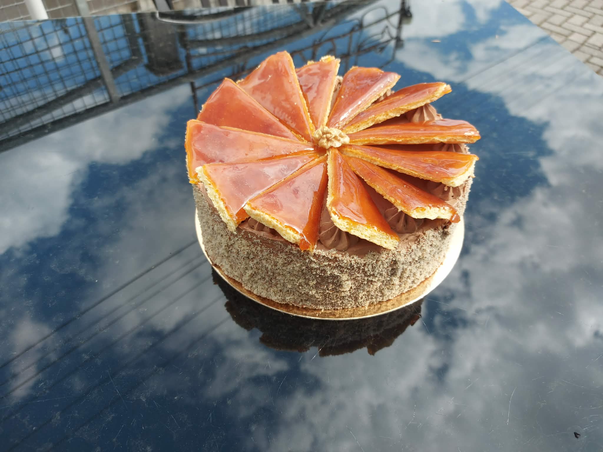 Egész gluténmentes Dobos torta karamellizált tetőlapokkal a terasz asztalán