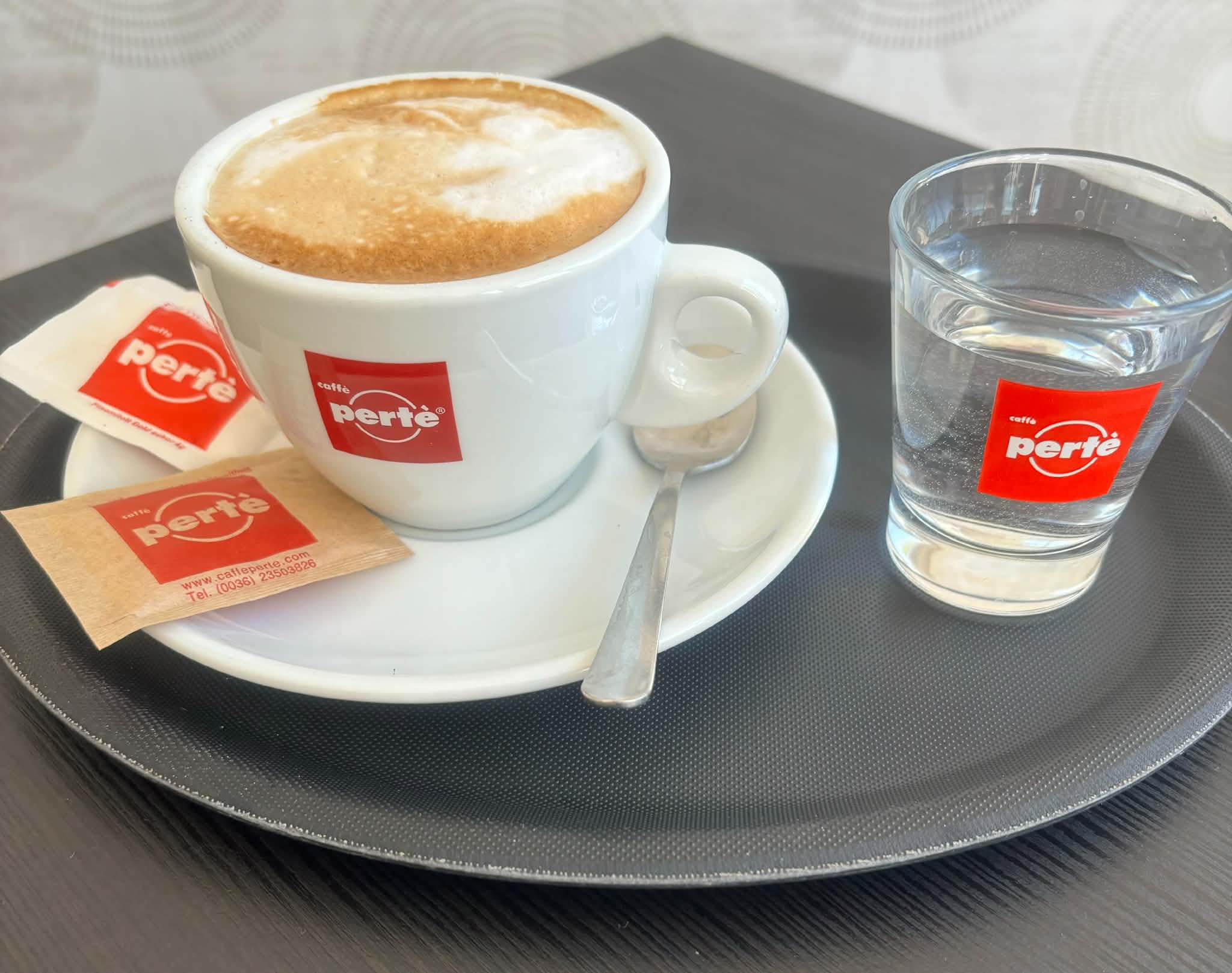 Cappuccino tálcán pohár vízzel a kávézóban