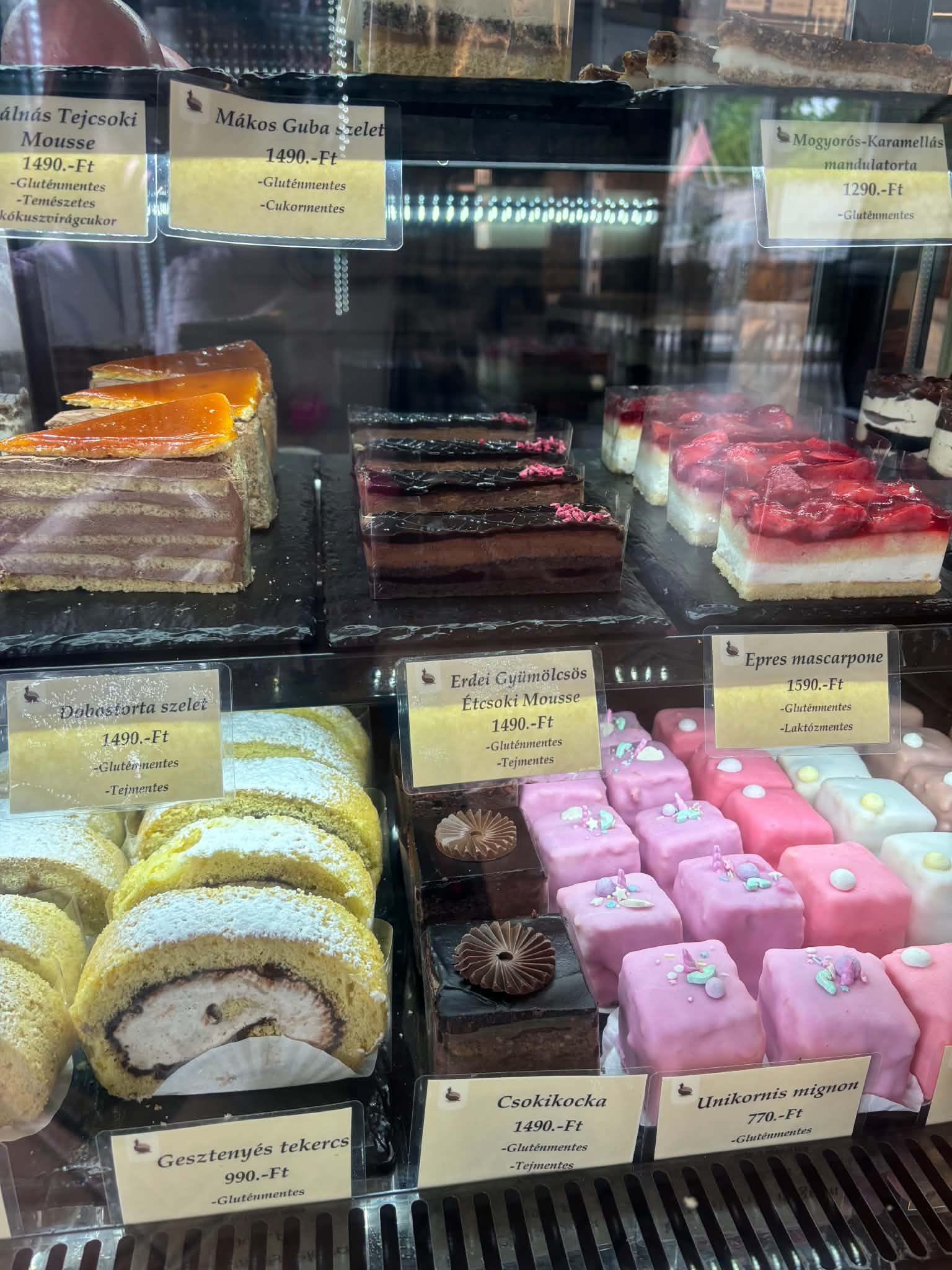 Gluténmentes sütemények a vitrinben: Dobostorta szelet, mousse-ok, tekercsek és mignonok árcímkékkel